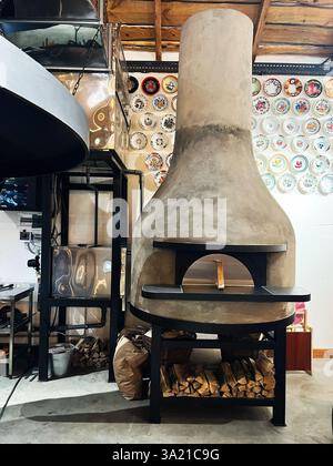 Velykyi Khodachkiv, Ukraine - 10 mars 2025 : un élégant four à bois exposé dans un cadre rustique avec des décorations murales Banque D'Images