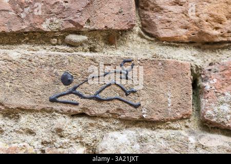 Drôle de figure de bâton d'un homme couché avec un verre de vin sur un mur à Certaldo, Toscane, Italie, Europe Banque D'Images