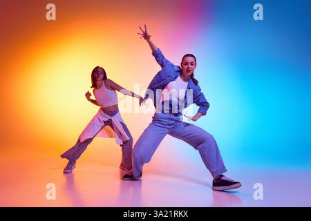 Deux danseurs hip-hop embrassant la culture de la rue avec des mouvements freestyle audacieux sous un éclairage dégradé au néon. Banque D'Images
