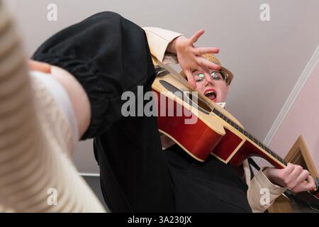 Vue à angle bas de la guitariste et de l'auteur-compositeur chanteuse strumming guitare classique et chante chanson. Perspective extraordinaire de la femme musicienne, selec Banque D'Images