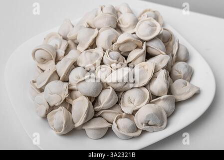 Une assiette pleine de pelmeni crus congelés, boulettes traditionnelles faites de pâte fourrée de viande Banque D'Images