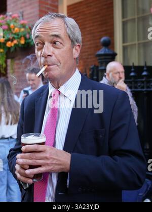Nigel Farage, leader réformiste britannique, fume devant le pub Westminster Arms à Westminster, Londres. Sir Keir Starmer a déclaré que le gouvernement "prendra des décisions" sur une interdiction potentielle de fumer en plein air dans un effort pour freiner les décès évitables et alléger les pressions sur le NHS. Date de la photo : jeudi 29 août 2024. Banque D'Images
