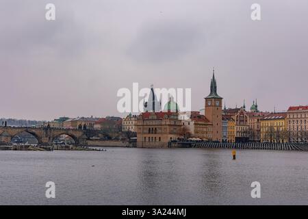 02-21-2025, Prague, la rivière Vltava qui coule sous le pont Charles à Prague par temps nuageux, reliant la tour du pont de la vieille ville et Malá Strana, crée un Banque D'Images