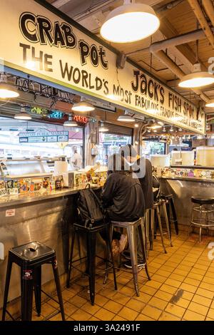 Deux personnes mangent au comptoir de Jack's Fish Spot dans le marché de Pike place, appréciant les fruits de mer frais. Banque D'Images
