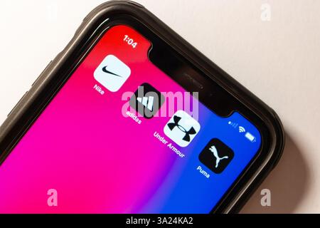 Les logos de Nike, Adidas, Under Armour et Puma sont affichés sur un iPhone, représentant le sport, la culture de rue et le style de vie sportif. Banque D'Images