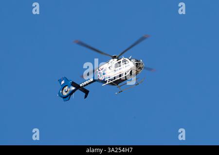 Palm Springs, Californie, États-Unis. 3 mars 2025. Cette photographie capture un hélicoptère médical Mercy Air en vol contre un ciel bleu clair. L'hélicoptère, un bimoteur Eurocopter EC135, est peint en blanc avec des accents bleus et rouges, avec le symbole reconnaissable Star of Life sur son fuselage. Le numéro d'enregistrement N58BAM est visible le long de la flèche de queue, qui porte également un autocollant de drapeau américain. L'avion est équipé d'un train d'atterrissage à patins et d'un rotor de queue fermé fenestron, une caractéristique de conception caractéristique de l'EC135. Le flou de mouvement des pales du rotor principal véhicule le R de l'hélicoptère Banque D'Images