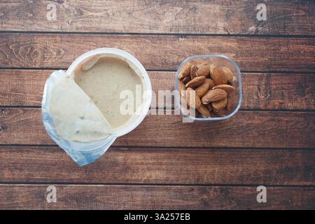Beurre d'amande crémeux et amandes entières sur table en bois Banque D'Images