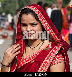 Femme indienne souriante en sari rouge vif traditionnel et foulard. Delhi, Inde. Banque D'Images