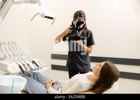 Femme dentiste photographiant avec un appareil photo professionnel le résultat de son travail en clinique. Banque D'Images