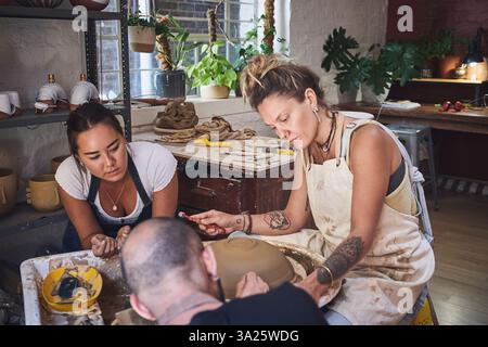 Formation des gens, de l'équipe et de la poterie en studio, travail ensemble et sculpture de l'argile pour l'artisanat céramique. Enseignement, équipement et aide à la leçon à Banque D'Images