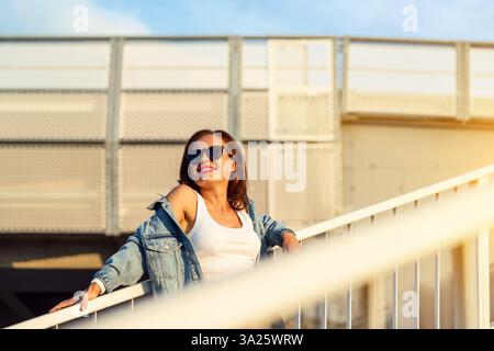 Portrait de Street-style de femme urbaine en tenue décontractée et lunettes de soleil en ville Banque D'Images