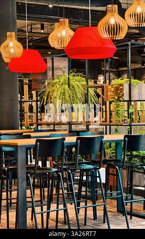 Intérieur de restaurant moderne avec des meubles en bois, des lumières suspendues et des plantes vertes - espace à manger confortable, design de café contemporain, décor élégant, atmosphère chaleureuse, restaurant urbain à la mode Banque D'Images
