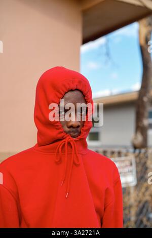 Une personne portant un sweat à capuche rouge regarde la caméra avec une expression neutre. Miami, Floride Banque D'Images
