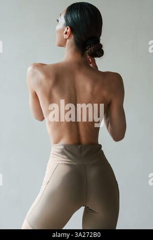 Vue arrière de la femme sportive qui est sans soutien-gorge à l'intérieur. Banque D'Images