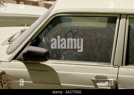 Une vieille fenêtre de voiture poussiéreuse avec un cœur tiré dans la saleté sur la surface vitrée. Téhéran, Iran Banque D'Images