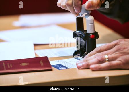 Gros plan d'une personne blanche caucasienne tamponnant un passeport étranger à la main au contrôle des frontières Banque D'Images