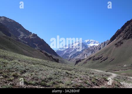 Une journée ensoleillée dans le parc national de l'Aconcagua, Mendoza, Argentine. Un sentier de randonnée mène à travers un terrain accidenté vers le majestueux sommet du mont Aconcagua Banque D'Images