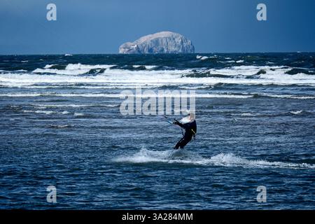 Dunbar, Royaume-Uni. 12 mars 2025. Un Kite surfer dans la baie de Belhaven près de Dunbar à l'extérieur d'Édimbourg, profite des vents violents du mercredi 12 mars 2025. Météo britannique le célèbre 'Bass Rock' peut également être vu dans le cadre, dans une partie de l'estuaire. Crédit image : Rob Gray/Alamy Live News Banque D'Images