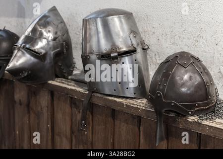 Casques médiévaux, fabriqués en métal et exposés sur une étagère en bois. Une représentation de l'art historique, de la tradition et de la protection en t médiéval Banque D'Images