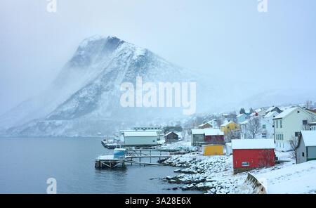 Village enneigé de Fjordgard et les montagnes enneigées escarpées de l'Oeyfjord sur l'île de Senja dans le nord de la Norvège Banque D'Images