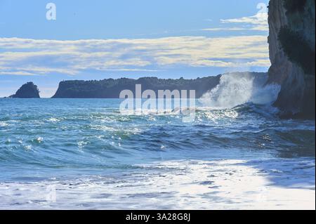 Vagues puissantes s'écrasant contre les rochers avec une vue panoramique sur la mer sous un ciel clair, Cathedral Cove, Hahei, Coromandel Peninsula, North Island, néo-zélandais Banque D'Images