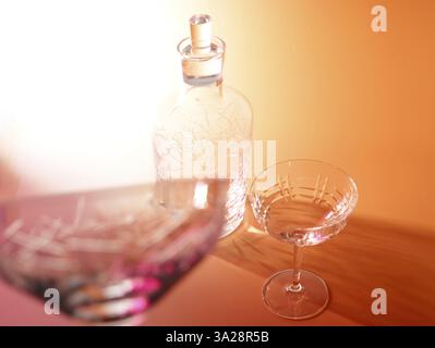 Art léger, verres divers, une bouteille vide devant un fond orange, plan studio Banque D'Images