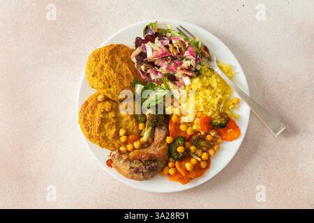 Un petit déjeuner sain avec des crêpes lentilles-courgettes, du millet, du cou de poulet rôti, des patates douces, du brocoli, carottes, pois chiches et salade fraîche Banque D'Images