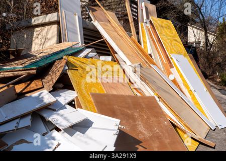 Une grande pile de pièces de meubles, de planches de bois et de portes jetées est empilée à l'extérieur sur un site de collecte. Banque D'Images