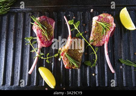 Côtelettes d'agneau crues assaisonnées et marinées aux herbes Banque D'Images