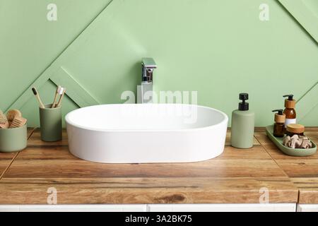 Commode avec lavabo, fournitures de bain près du mur vert dans la salle de bains Banque D'Images