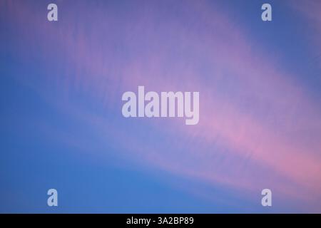 Alors que le crépuscule s'installe, de doux nuages roses s'étendent sur un ciel clair, créant une atmosphère sereine. Les teintes de rose et de bleu se mélangent magnifiquement, signalant Banque D'Images
