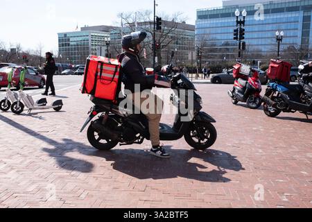 Un livreur de nourriture basé sur une application est vu près de Union Station à Washington, DC, États-Unis le 12 mars 2025. Aux États-Unis, les repas sont généralement livrés par des coursiers en utilisant diverses méthodes, y compris les voitures, scooters, vélos, ou à pied. Banque D'Images
