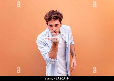 jeune homme donnant le baiser avec la main regardant la caméra Banque D'Images