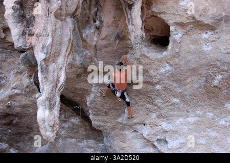 Un grimpeur escaladant les falaises de calcaire escarpées de Phra Nang Beach, en Thaïlande, présentant les célèbres formations surplombantes de la région Banque D'Images