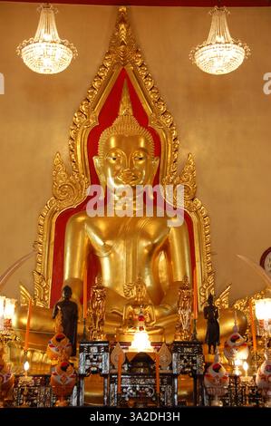Statue de Bouddha doré au temple Wat Traimit à Bangkok, entourée de décorations ornées et de lustres dans une salle richement ornée Banque D'Images