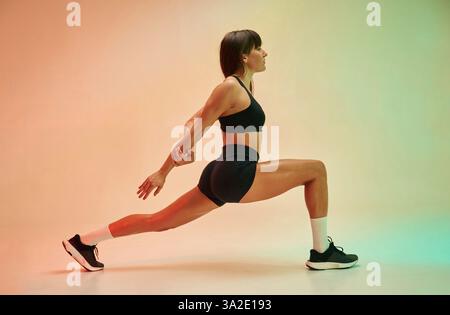Vue latérale, exercice. Jeune femme en vêtements de fitness est dans le studio. Banque D'Images