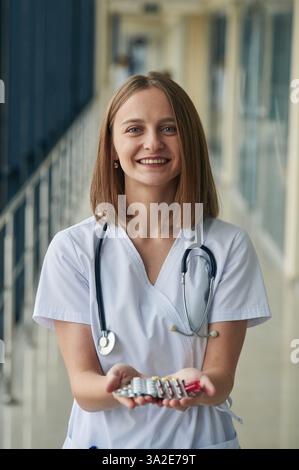 Bouquet de pilules dans les mains. Docteur femme en manteau blanc est dans le hall. Banque D'Images