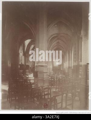 Photographie d'Eugène Atget montrant l'intérieur de l'église Saint-Séverin à Paris. L'image met en valeur l'architecture gothique de l'église, y compris ses arches et ses vitraux. Atget capture l'atmosphère solennelle et les détails architecturaux complexes, mettant en valeur l'importance historique de cette église du XVe siècle. Banque D'Images
