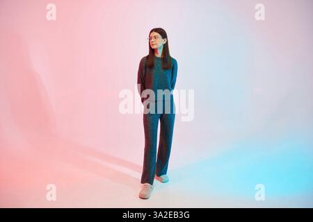 Une jeune femme en lunettes se tient debout dans le studio. Banque D'Images