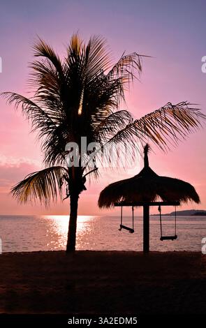 Balancez-vous dans un parasol avec un palmier sur la côte ouest de l'île de Gili Air St coucher du soleil, Lombock, Gili Air Banque D'Images