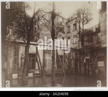 Cette photographie d'Eugène Atget représente un petit bâtiment qui abritait autrefois le cloître de l'ancien charnier de Saint Séverin, qui allait bientôt être démoli. L'image capture l'architecture historique avant sa disparition. Banque D'Images