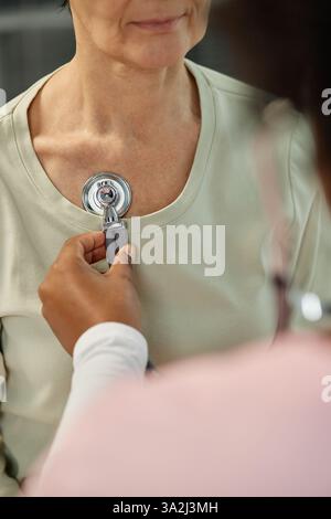 Médecin examinant le patient à l'aide d'un stéthoscope, vérifiant la fréquence cardiaque et les bruits pulmonaires. Concentrez-vous sur les soins attentionnés du professionnel de santé, le patient montrant un comportement calme pendant la procédure Banque D'Images