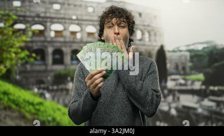 Homme hispanique à l'extérieur du colisée romain étonné tenant des roubles russes. Banque D'Images