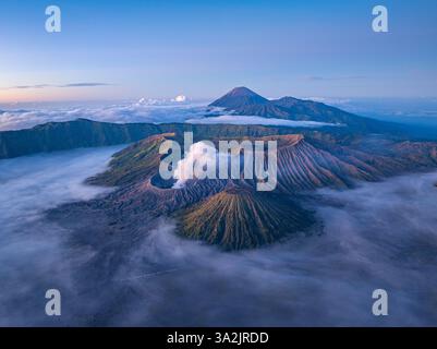 Vue aérienne du Mont bromo à couper le souffle entouré de brume et de paysages spectaculaires. Volcan actif en Indonésie, la douce lumière du matin se met en évidence Banque D'Images