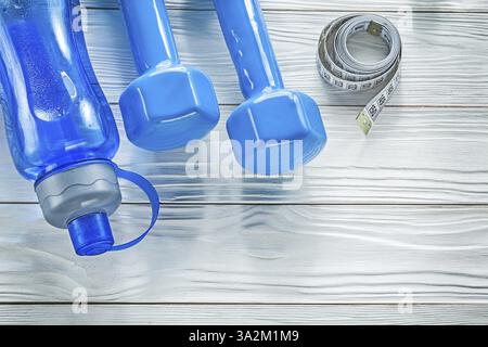 Ensemble de ruban à mesurer bouteille d'eau bleu haltères sur concept de fitness de planche en bois Banque D'Images