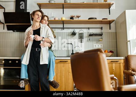 Couple aimant partage un moment chaleureux dans leur cuisine confortable, embrassant tout en sirotant des boissons. Banque D'Images