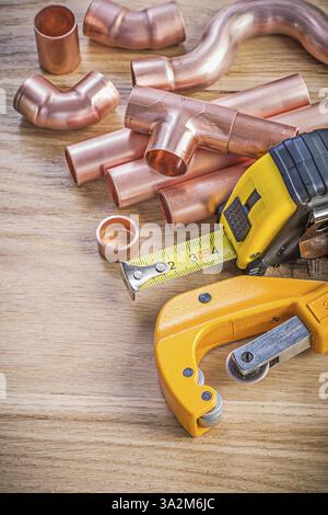 Ensemble de fixations de coupe-tuyau d'eau en cuivre ligne de ruban sur le concept de plomberie de planche en bois Banque D'Images