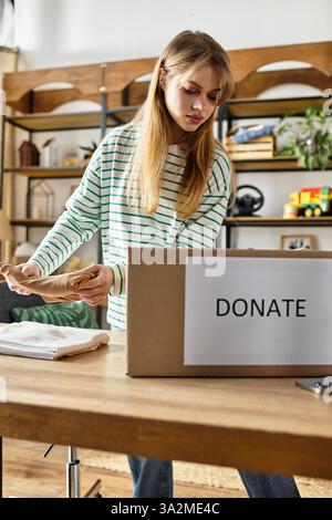 Une jeune femme trie ses vêtements pour le don, encourageant la durabilité. Banque D'Images