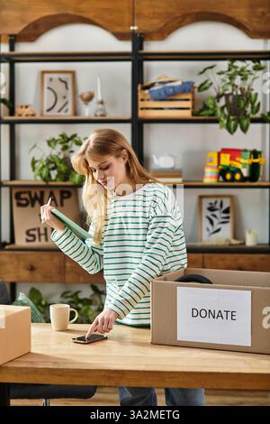 Une jeune femme trie des vêtements pour don, en utilisant un smartphone, une vie durable. Banque D'Images