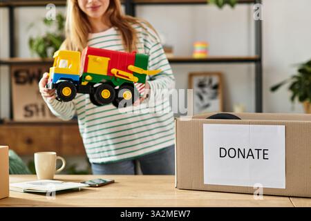 Une jeune femme trie les jouets, se préparant à les donner pour un mode de vie durable. Banque D'Images